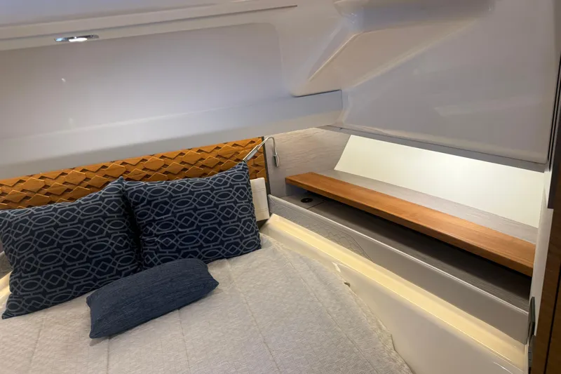  Yacht Photos Pics 2023 Tiara Yachts 48 LS cabin interior with patterned pillows and wooden shelf.