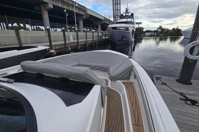  Yacht Photos Pics 2023 Tiara Yachts 48 LS docked near a bridge, with a luxury yacht in the background.