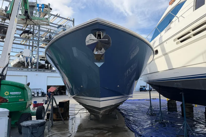  Yacht Photos Pics 2023 Tiara Yachts 48 LS in a boatyard, surrounded by equipment and other vessels.