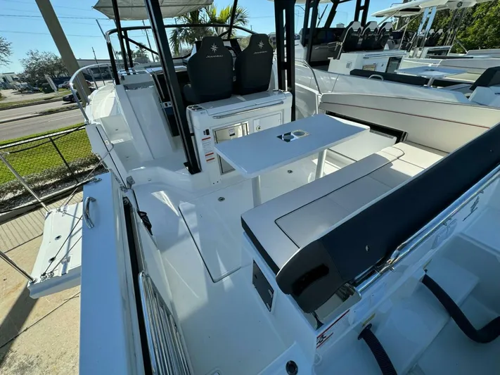  Yacht Photos Pics 2024 Jeanneau 9.0 Walk boat interior with seating and table, showcasing modern design.
