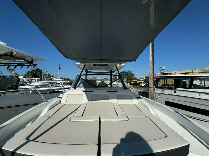  Yacht Photos Pics 2024 Jeanneau 9.0 Walk boat with spacious deck and canopy, docked under clear blue sky.