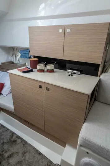  Yacht Photos Pics 2024 Jeanneau 9.0 Walk interior with modern kitchenette and wooden cabinetry.
