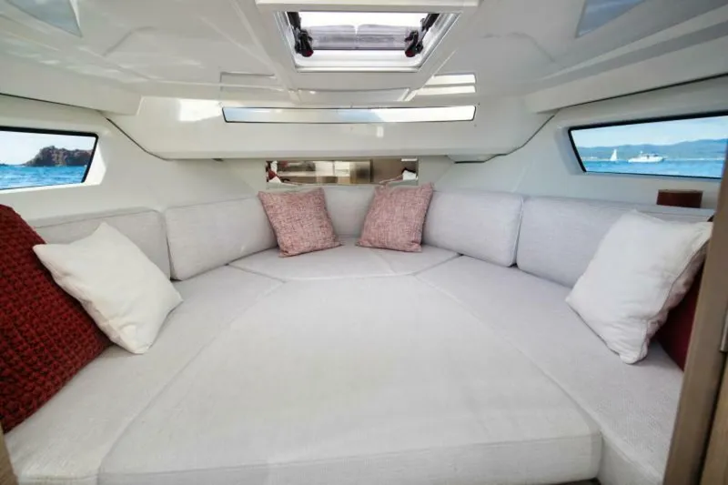  Yacht Photos Pics 2024 Jeanneau 9.0 Walk interior with cozy seating and decorative pillows.