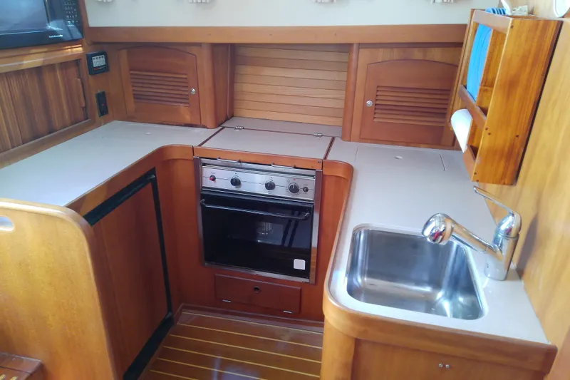 Kathrine E. Yacht Photos Pics 2002 Sabreline 36 Express yacht kitchen with stove, sink, and wooden cabinetry.