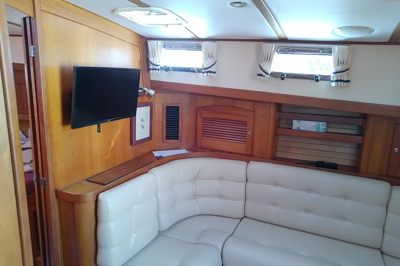Kathrine E. Yacht Photos Pics Interior of 2002 Sabreline 36 Express yacht with white seating and mounted TV.