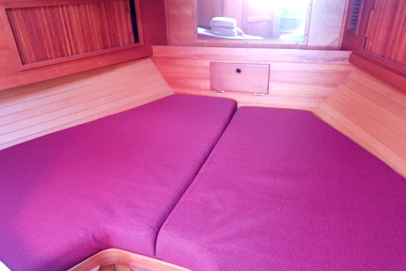 Kathrine E. Yacht Photos Pics Cozy cabin interior of 2002 Sabreline 36 Express with purple cushions and wooden paneling.
