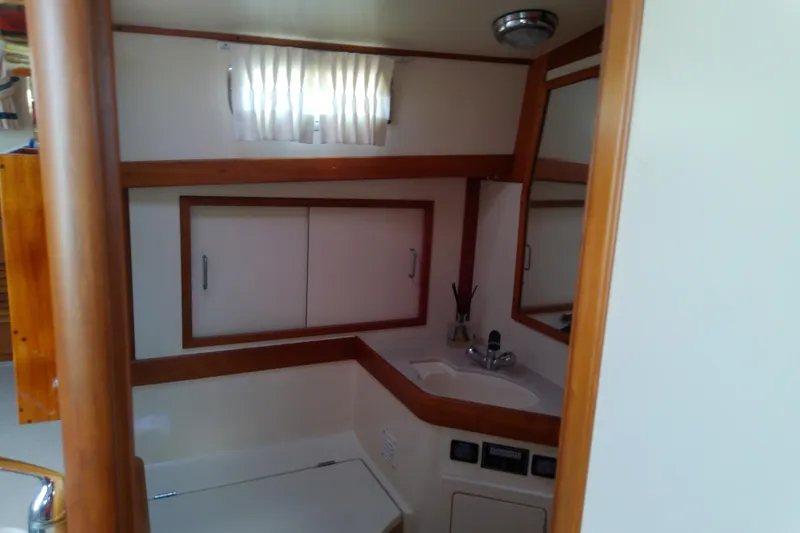 Kathrine E. Yacht Photos Pics 2002 Sabreline 36 Express yacht bathroom with sink, mirror, and storage cabinets.
