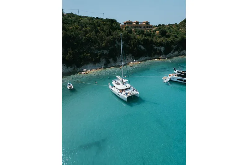  Yacht Photos Pics 2017 Lagoon 42 catamaran anchored in clear turquoise waters near a lush coastline.