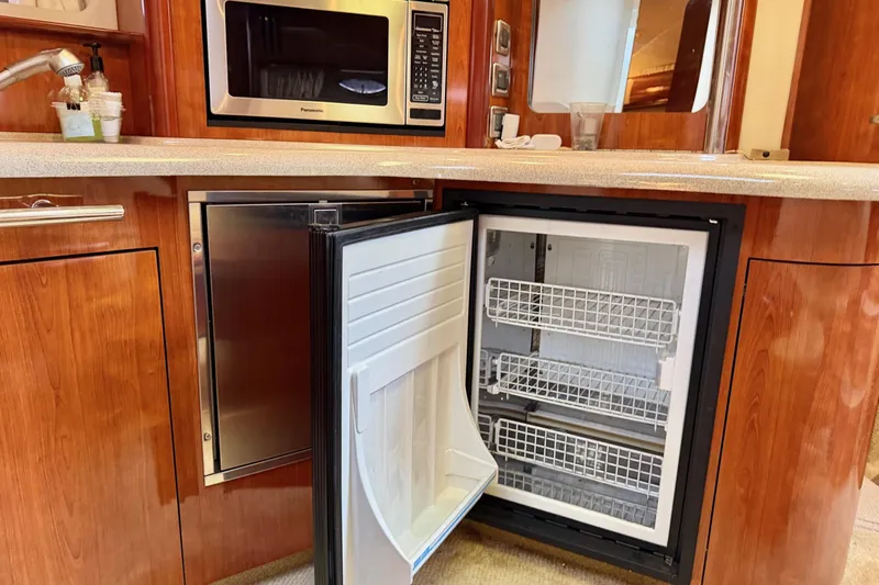  Yacht Photos Pics 2004 Sea Ray 420 Sundancer galley with open fridge, microwave, and wooden cabinetry.