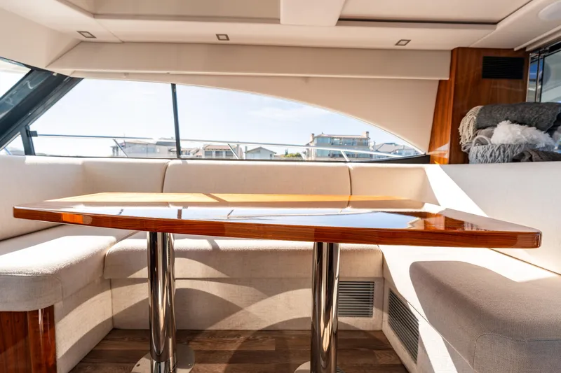 Ventures64 Yacht Photos Pics Luxurious interior of 2022 Riviera 4800 Sport Yacht with elegant wooden table and plush seating.