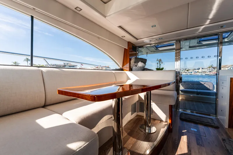 Ventures64 Yacht Photos Pics Interior of 2022 Riviera 4800 Sport Yacht with elegant seating and wooden table.