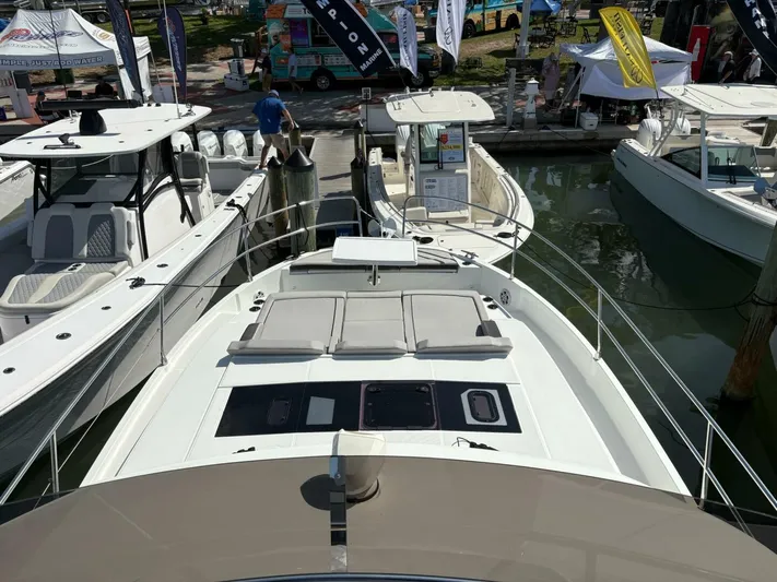  Yacht Photos Pics 2025 Jeanneau 1295 FLY yacht displayed at a boat show, docked alongside other vessels.