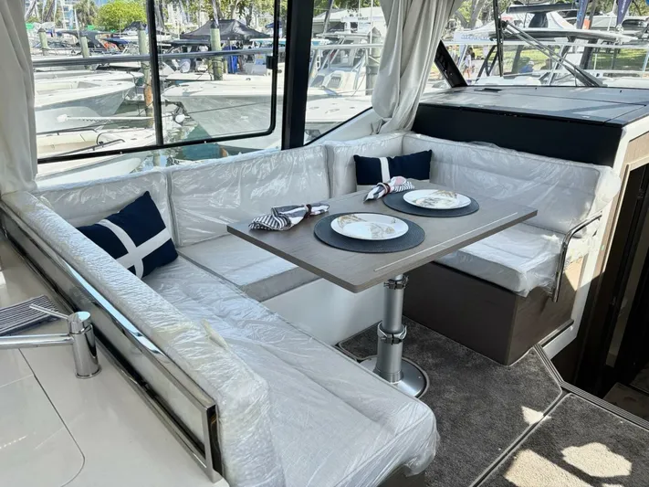  Yacht Photos Pics 2025 Jeanneau 1295 FLY yacht interior with dining area and cushioned seating.