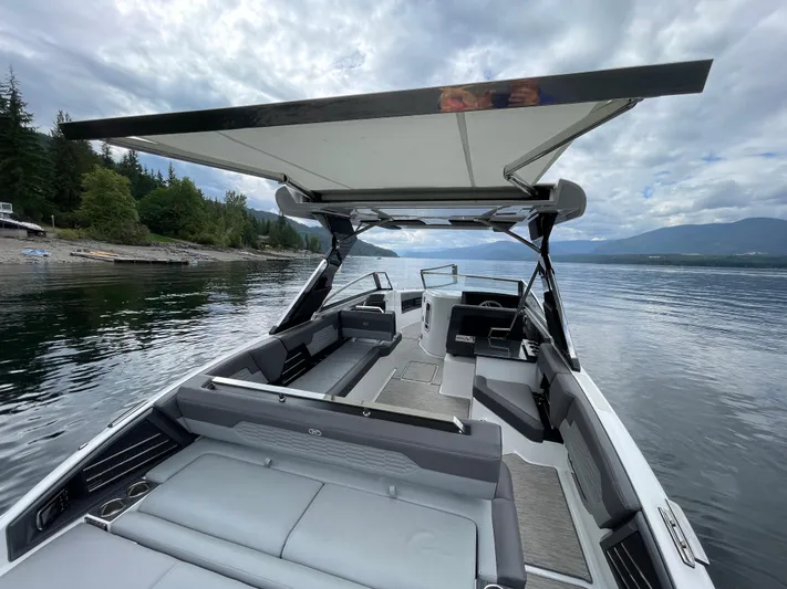  Yacht Photos Pics 2020 Cobalt A29 boat with canopy on a serene lake, surrounded by trees and mountains.