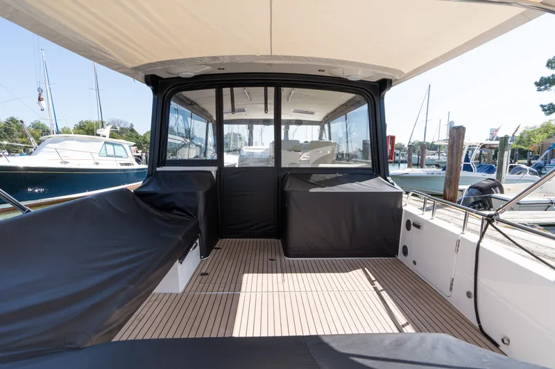 Middle Path Yacht Photos Pics 2023 MJM 4 boat interior with covered seating and docked yachts in background.