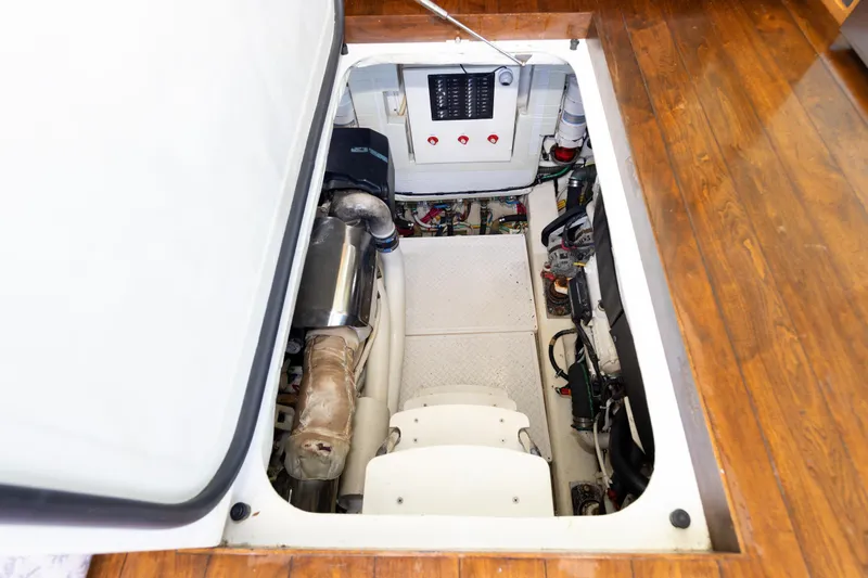 Salty Sam Yacht Photos Pics Engine compartment of a 2014 Tiara 5000 Coupe with visible components and wooden flooring.