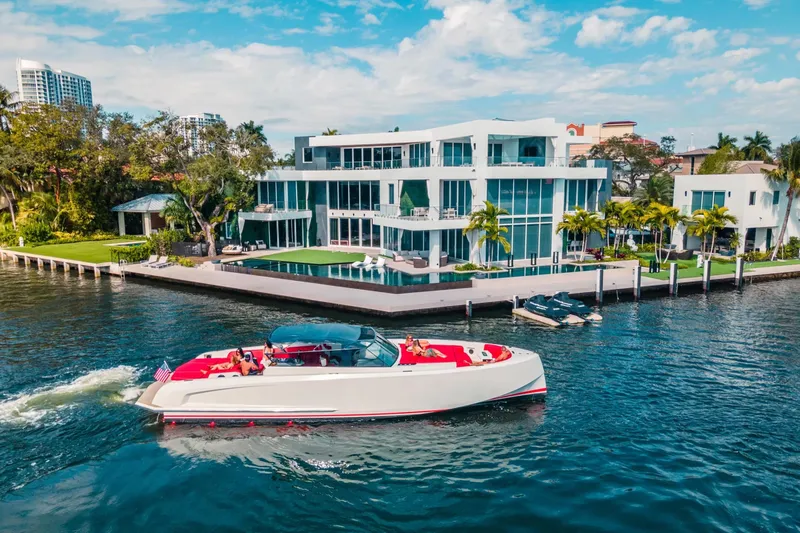  Yacht Photos Pics 2016 Vanquish Yachts 48 cruising near a luxurious waterfront mansion under a clear blue sky.