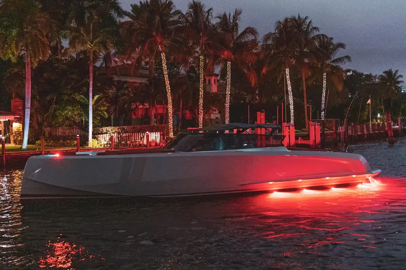  Yacht Photos Pics 2016 Vanquish Yachts 48 illuminated at night, surrounded by palm trees and waterfront scenery.