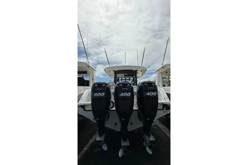  Yacht Photos Pics 2022 Boston Whaler 380 Outrage with triple 400 horsepower engines, docked under a cloudy sky.