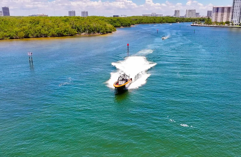  Yacht Photos Pics 2022 Midnight Express 43 Open cruising on a scenic waterway with lush greenery and cityscape.