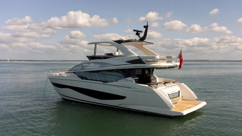 Madness V Yacht Photos Pics Luxurious 2022 Pearl 62 yacht on calm waters under a partly cloudy sky.