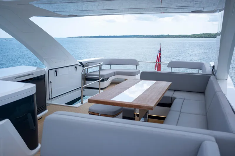 Madness V Yacht Photos Pics Luxurious Pearl 62 yacht interior with seating and table, overlooking serene ocean view, 2022 model.