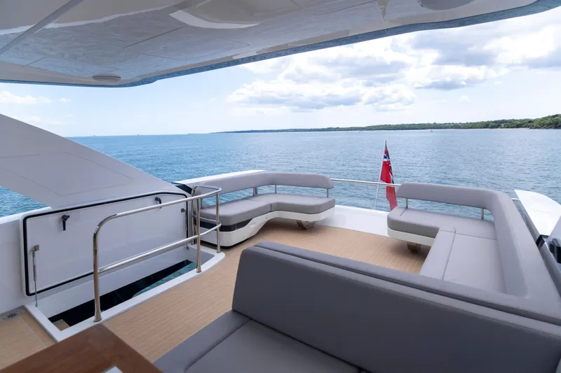Madness V Yacht Photos Pics Luxurious Pearl 62 yacht deck with modern seating, ocean view, and flag, 2022 model.