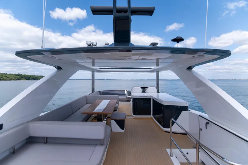 Madness V Yacht Photos Pics Luxurious 2022 Pearl 62 yacht deck with seating, table, and ocean view.