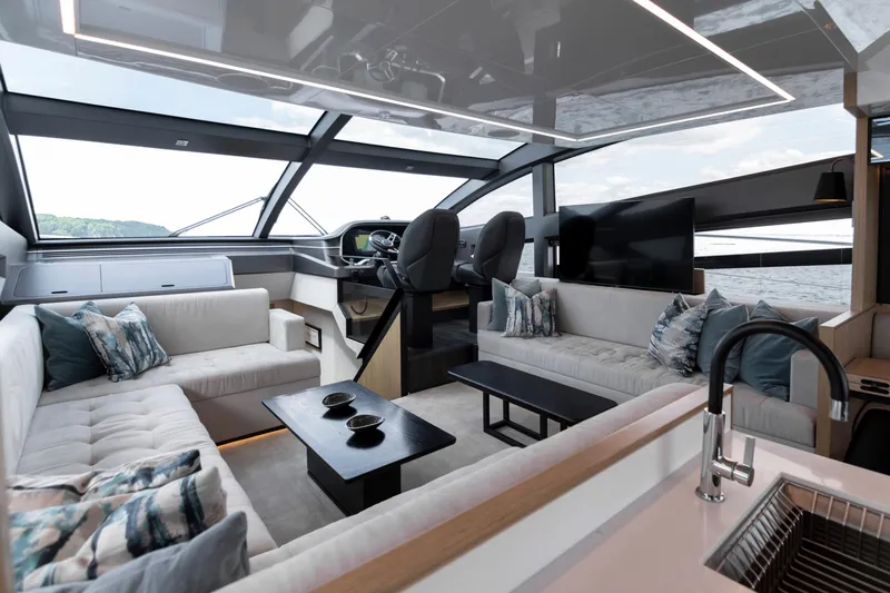 Madness V Yacht Photos Pics Luxurious interior of 2022 Pearl 62 yacht with modern seating and panoramic windows.