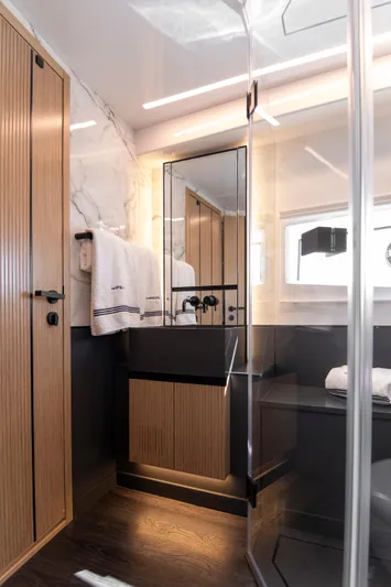 Madness V Yacht Photos Pics Modern yacht bathroom with wood accents, sleek fixtures, and a glass shower in a 2022 Pearl 62.