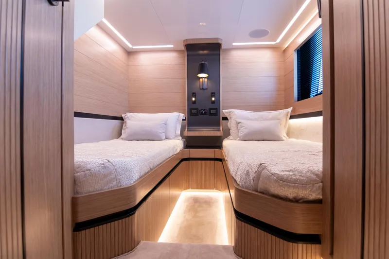 Madness V Yacht Photos Pics Luxurious twin cabin interior of 2022 Pearl 62 yacht with modern lighting and wood finish.