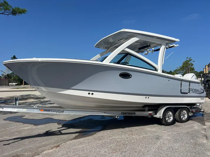  Yacht Photos Pics 2025 Robalo R257 Dual Console boat on trailer, parked outdoors under clear blue sky.