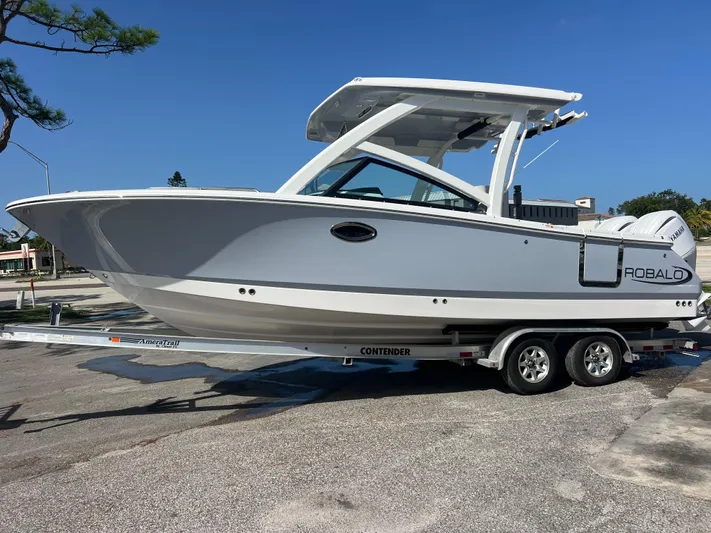  Yacht Photos Pics 2025 Robalo R257 Dual Console boat on trailer, parked outdoors under clear blue sky.