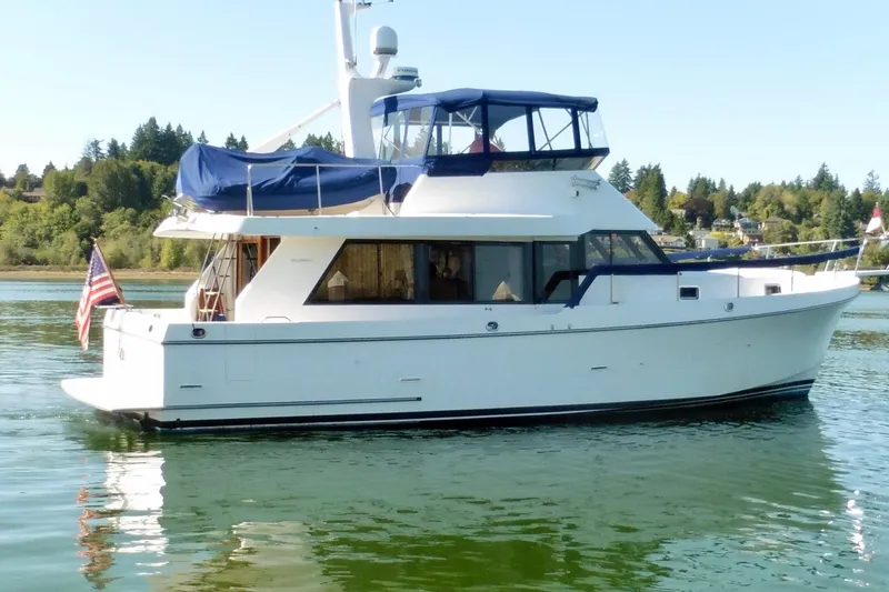 Kokomo Yacht Photos Pics 2000 Ocean Alexander 423 Classico yacht on calm water, featuring blue canopy and American flag.