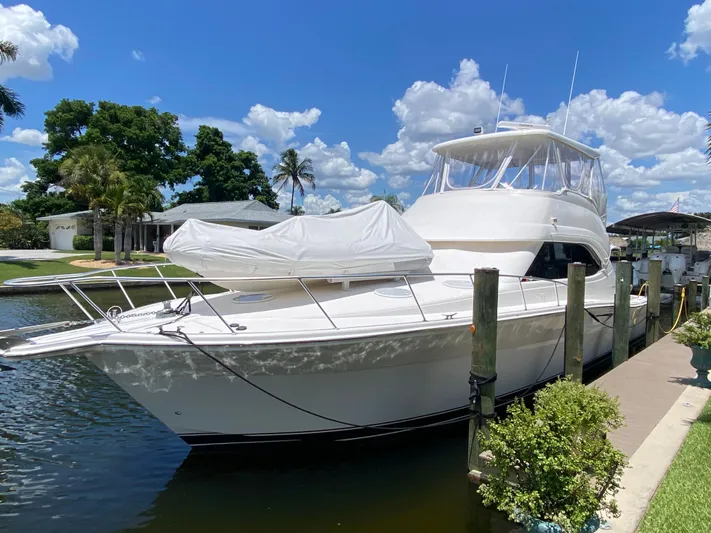 Pretty Fine Yacht Photos Pics 2003 Riviera 47 Convertible yacht docked by a sunny waterfront with palm trees.