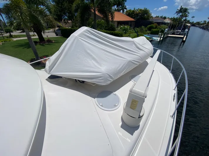 Pretty Fine Yacht Photos Pics 2003 Riviera 47 Convertible yacht with covered equipment on deck, docked by a canal.