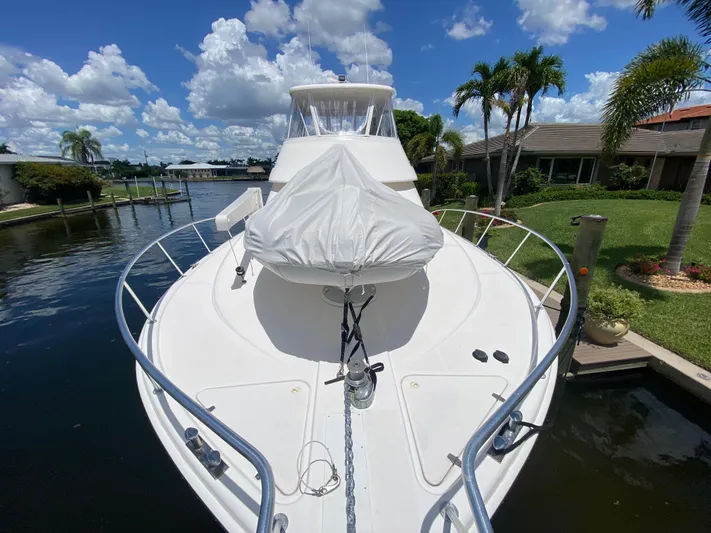 Pretty Fine Yacht Photos Pics 2003 Riviera 47 Convertible yacht docked, surrounded by lush greenery and clear blue skies.