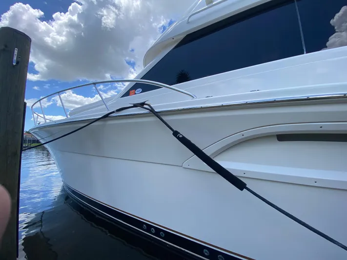 Pretty Fine Yacht Photos Pics 2003 Riviera 47 Convertible yacht docked under a cloudy sky.