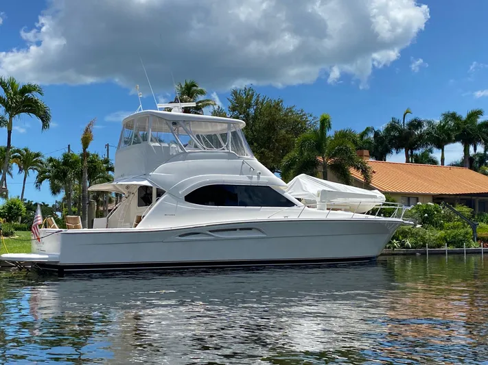 Pretty Fine Yacht Photos Pics 2003 Riviera 47 Convertible yacht docked by tropical waterfront home.