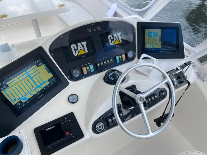 Pretty Fine Yacht Photos Pics Control panel of a 2003 Riviera 47 Convertible yacht with navigation screens and steering wheel.