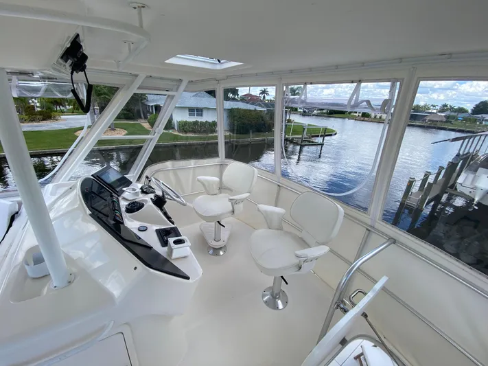 Pretty Fine Yacht Photos Pics 2003 Riviera 47 Convertible yacht interior with helm, white chairs, and waterfront view.