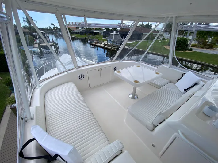 Pretty Fine Yacht Photos Pics 2003 Riviera 47 Convertible yacht interior with white seating and table, docked by a scenic waterfront.