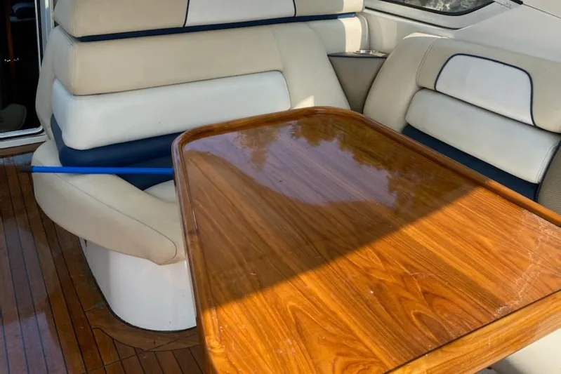 Dealer-ship Yacht Photos Pics 2004 Fountain 48 Express Cruiser interior with wooden table and cushioned seating.