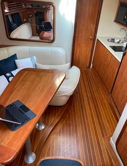 Dealer-ship Yacht Photos Pics 2004 Fountain 48 Express Cruiser interior with wooden flooring, dining area, and compact kitchen.