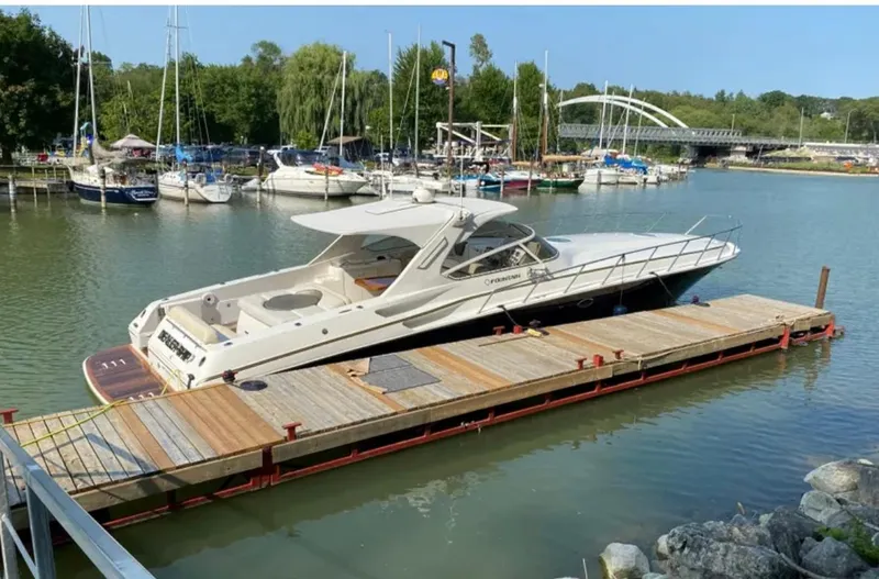 Dealer-ship Yacht Photos Pics 2004 Fountain 48 Express Cruiser docked at a marina with surrounding boats and greenery.