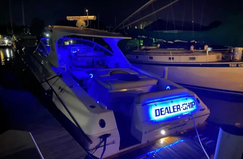 Dealer-ship Yacht Photos Pics 2004 Fountain 48 Express Cruiser with blue LED lights docked at night.