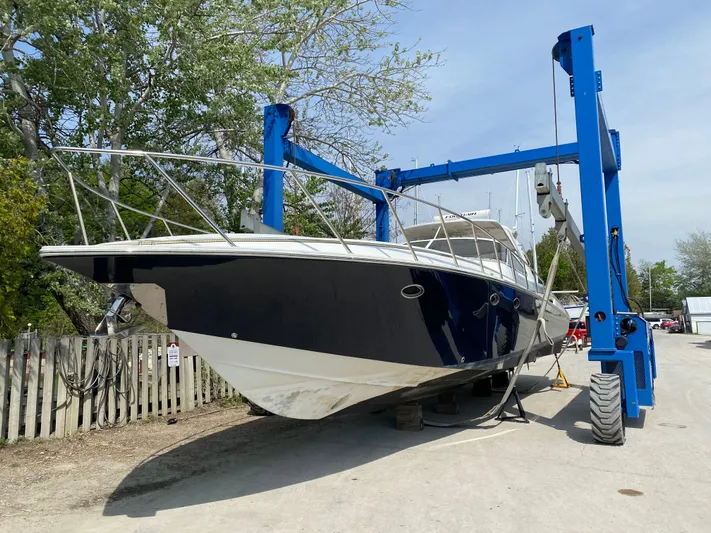 Dealer-ship Yacht Photos Pics 2004 Fountain 48 Express Cruiser on a blue boat lift, surrounded by trees.