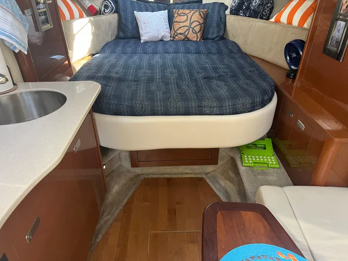 Baileys Dinghy Yacht Photos Pics 2010 Sea Ray 350 Sundancer cabin interior with bed, pillows, and kitchenette.