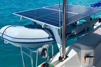 Nautitech 40 Open 2022 catamaran with solar panels and dinghy in a scenic marina.
