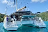 2022 Nautitech 40 Open catamaran anchored in clear blue water, with lush green hills in the background.